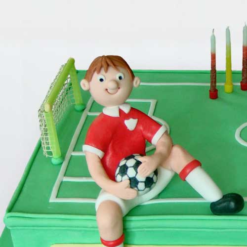 Boys football birthday cake. Football pitch with boy sitting on it. 